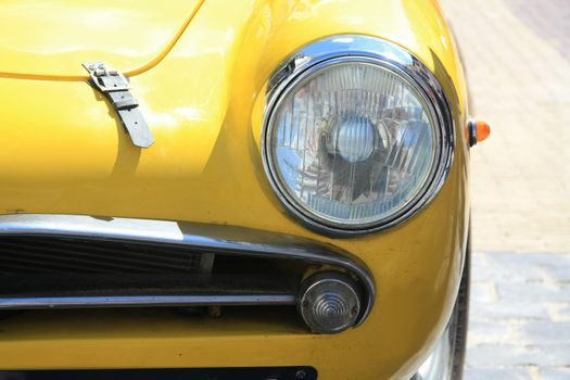 A yellow, vintage Italian sportcar in detail