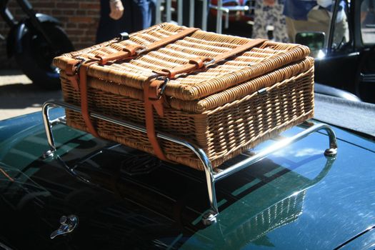 A wicker suitcase on a classic green car