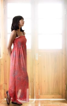 Oriental girl thinking and standing in front of door with light.