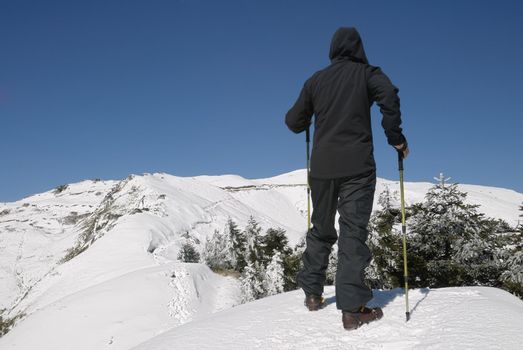 Mountaineer walking on snow mountain under blue sky.