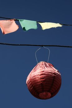 paper lantern hangs from a wire against a blue sky