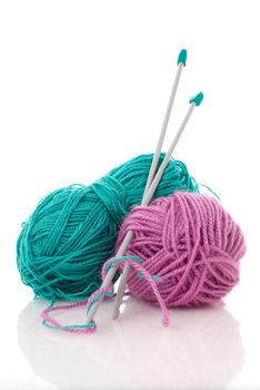 Balls of green and pink  knitting wool or yarn, with silver knitting needles.