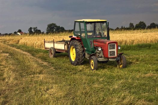 An old farm tractor on the side of an agriculture field in South Poland