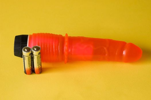 Red vibrator with batteries on yellow background