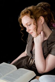 Beautiful girl with red hair reading a book