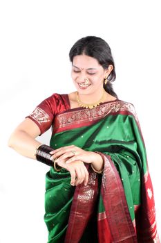 A beautiful Indian woman in a green sari wearing the traditional jewelery on the occasion of Diwali festival in India, on white studio background.