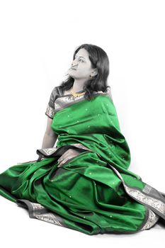 A beautiful Indian woman wearing a traditional green sari and jewlery, on white background.