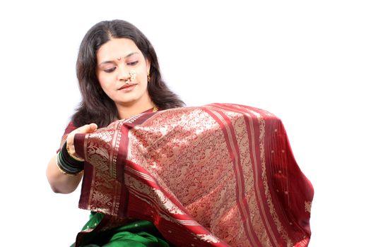 A beautiful Indian woman checking the design on her new traditional sari, on white studio background.