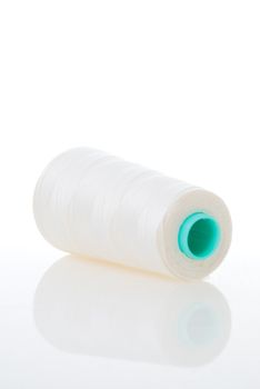 Bobbin of white thread isolated on white background with reflection.