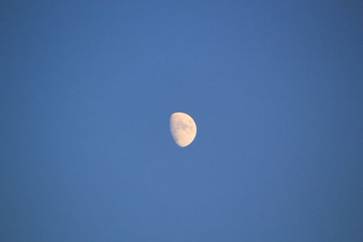 Partial moon in a deep blue sky