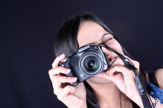 A beautiful Indian teenage girl clicking a photograph with a 6 megapixel digital camera.