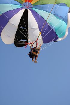 A view of an Indian couple landing from a parasail ride with a colorful parachute, on a tropical beach in their holidays.