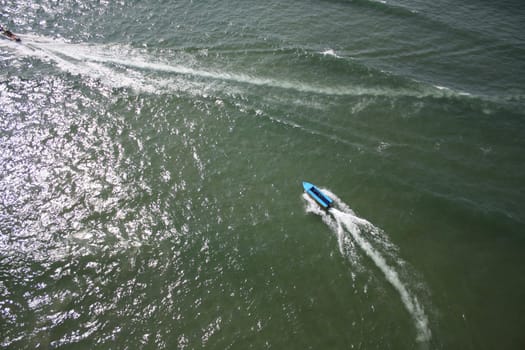 An aerial view of a speedboat in green ocean water.