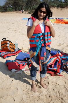 A beautiful Indian woman wearing the safety gear for parasailing, on an Indian beach.