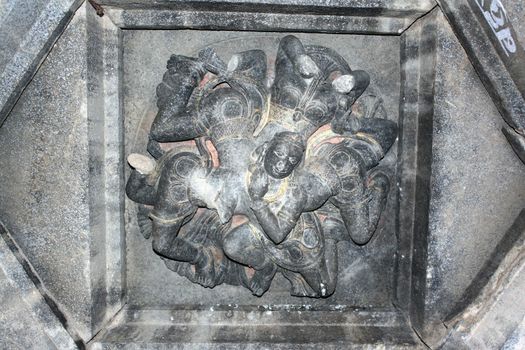 A Sculpture of Hindu God Krishna (in his baby form) on the ceiling of an ancient temple (thousands of years old). The speciality of this sculpture is that with a single head of the diety at the center, there are 8 body positions surrounding it which all seem natural.