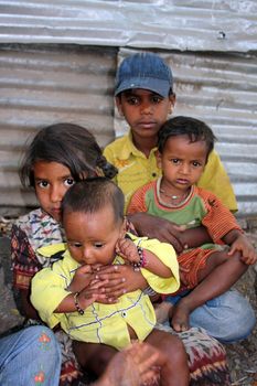 Poor sick chilren sitting on the sides of a street, in India.