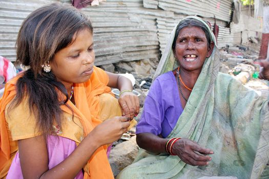 A streetside teenage girl is worried as her jobless grandmother is crying being jobless, in India.