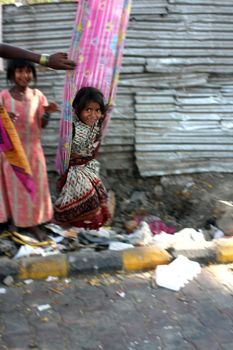 A beautiful picture in motion of a poor beggar girl from India, having fun on a swing made of a sari (traditional clothing) tied to a tree.