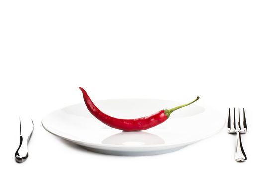 one red chili served on a plate with knife and fork