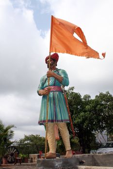 A statue of an ancient warrior from India, holding the traditional hindu flag.