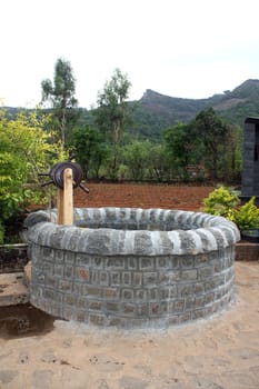 An old well with a wooden water-drawing wheel, in India.