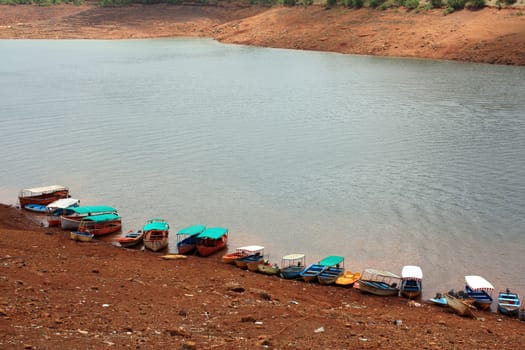 A line of boats anchored on the side of a lake for tourists, in India.