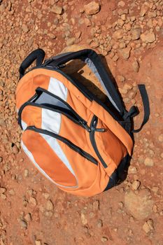 A haversack / Backpack for trekking, lying on a red rocky surface.