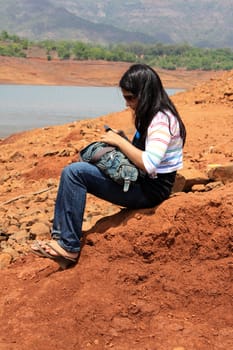 A lonely Indian woman sitting on the banks of a river, waiting for someone.