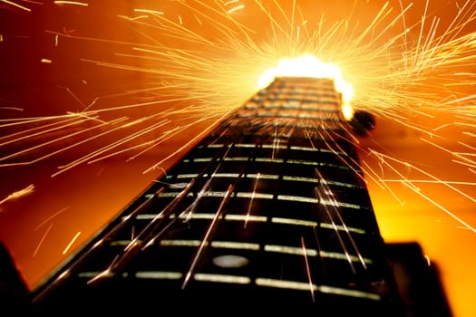 Powerful sparks flying off the top of a fretboard of an electric guitar.