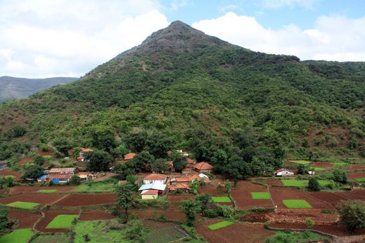 A beautiful Indian village situated in a valley in the high mountains and paddy fields.