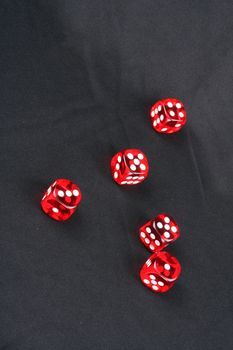Red casino dices scattered on a black fabric.