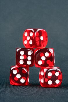 A pyramid of red casino dices on a black fabric.