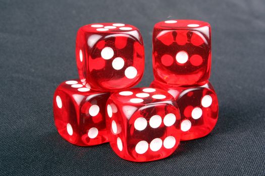 Five red casino dices on a black fabric.