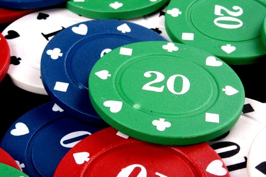 A background with a view of a green gambling chip of 20 lying on a heap of other colorfup chips.