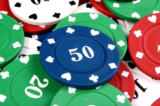 A background with a view of a blue gambling chip of 50 lying on a heap of other colorfup chips.