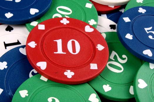 A background with a view of a red gambling chip of 10 lying on a heap of other colorfup chips.