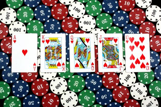A poker hand of royal flush on the background of casino chips.