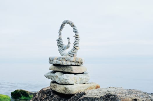Spiral of pebbles on the top of boulder at the sea