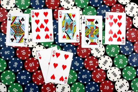 A poker hand called flush consisting of 5 cards of the same deck (hearts in this picture), on colorful gambling chips.