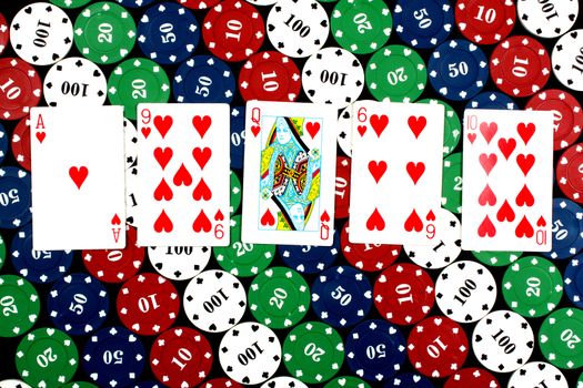 A poker hand of flush consisting of all heart cards, on casino counters background.