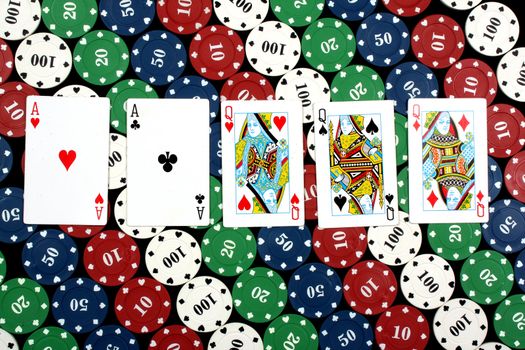 A background with a view of a hand of FULL HOUSE in a game of poker, on colorful gambling chips.