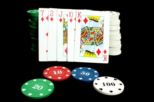 A poker hand of flush consisting 5 cards of the same deck, leaning on stacks of gambling chips.