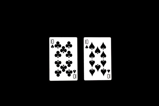 A poker hand called 'Two of a Kind', consisting of two 10s in this image, on black studio background.