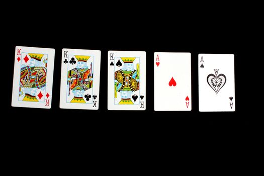 A poker hand of 'full house' consisting of two aces and three kings, on black background.