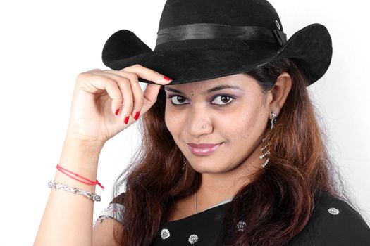 A portrait of a beautiful Indian woman in a traditional saree wearing a hat.