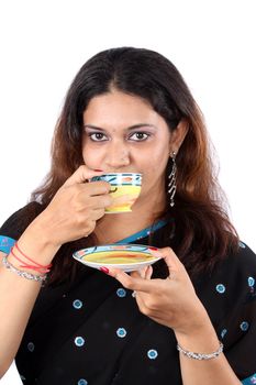 An Indian woman in a traditional saree, drinking coffee / tea.