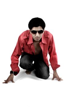 A glamorous shot of a handsome Indian guy in a red shirt posing on a white fabric, on white studio background.