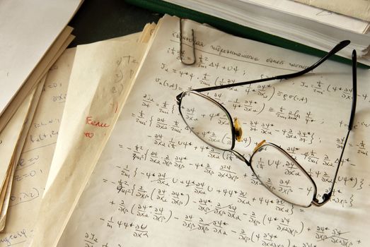 glasses over physics formulas and calculations written on paper