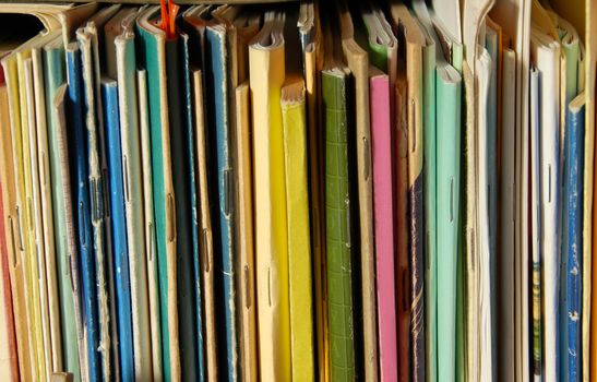 various colorful books and notebooks covers on bookshelf