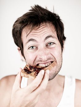 Man eating breakfast toast with peanut butter and jelly. Funny portrait photo of young caucasian male. 